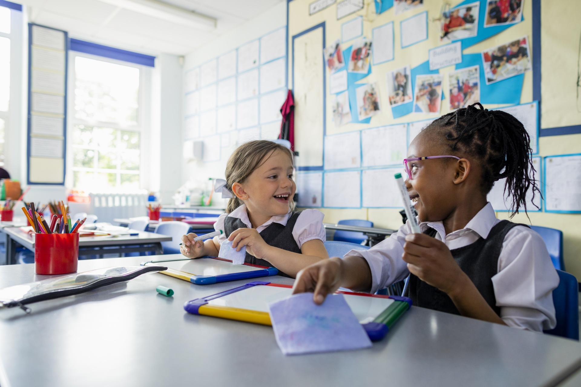 Two children talking with mini whiteboards